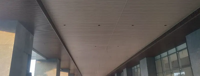 Long linear timber-finish soffit running the length of a commercial ground-floor arcade