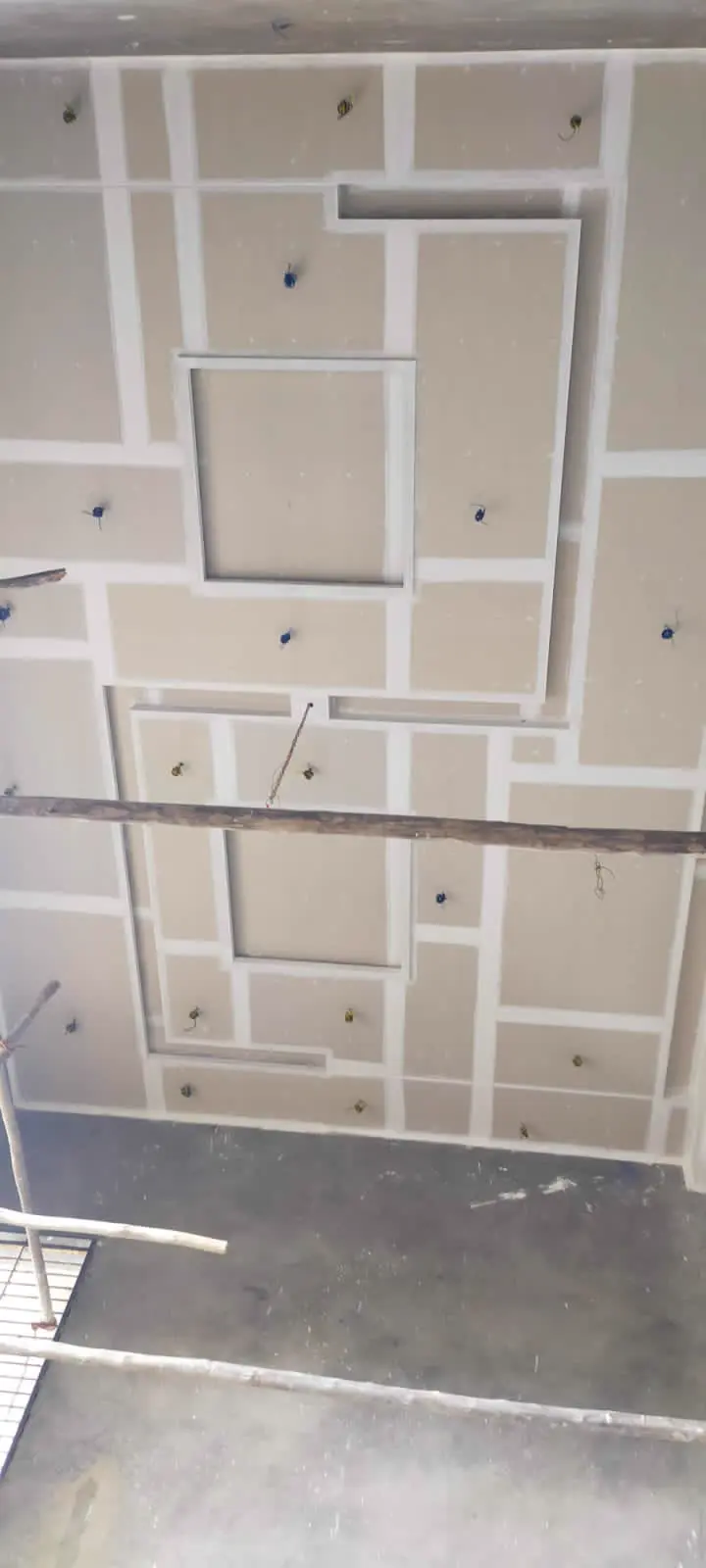 Large geometric gypsum ceiling grid under construction with jointing compound applied and wiring drops in place