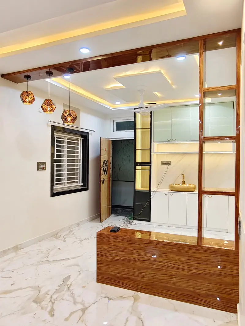 Living and dining area with a layered false ceiling, pendant lights and a wooden partition screen